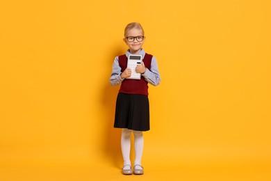 Photo of Little girl with calculator pretending to be accountant on orange background. Dreaming of future profession