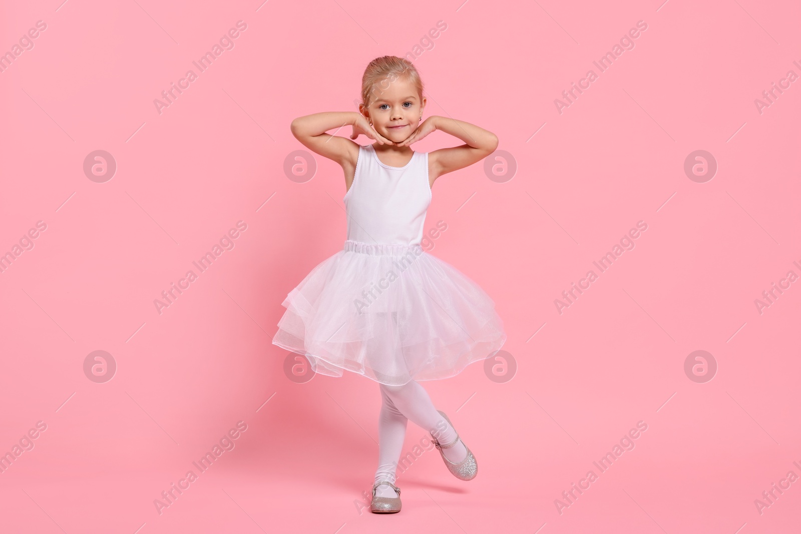 Photo of Little girl pretending to be ballerina on pink background. Dreaming of future profession