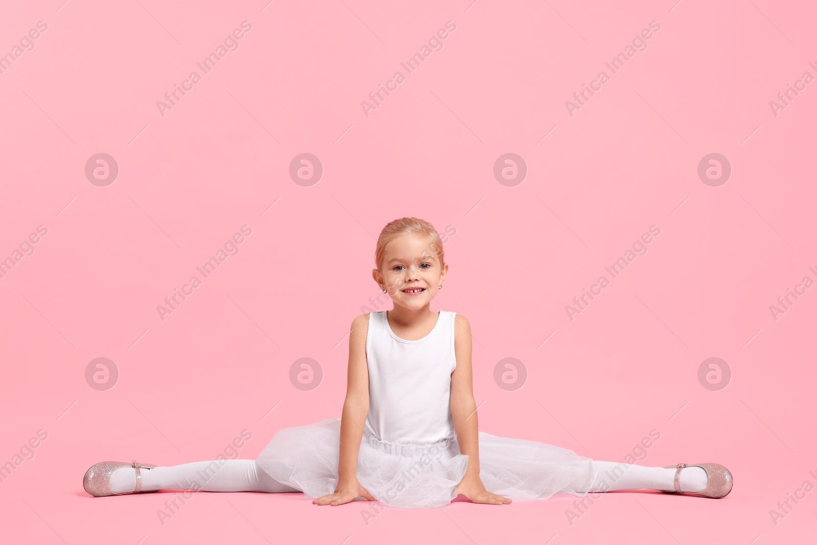 Photo of Little girl pretending to be ballerina on pink background. Dreaming of future profession