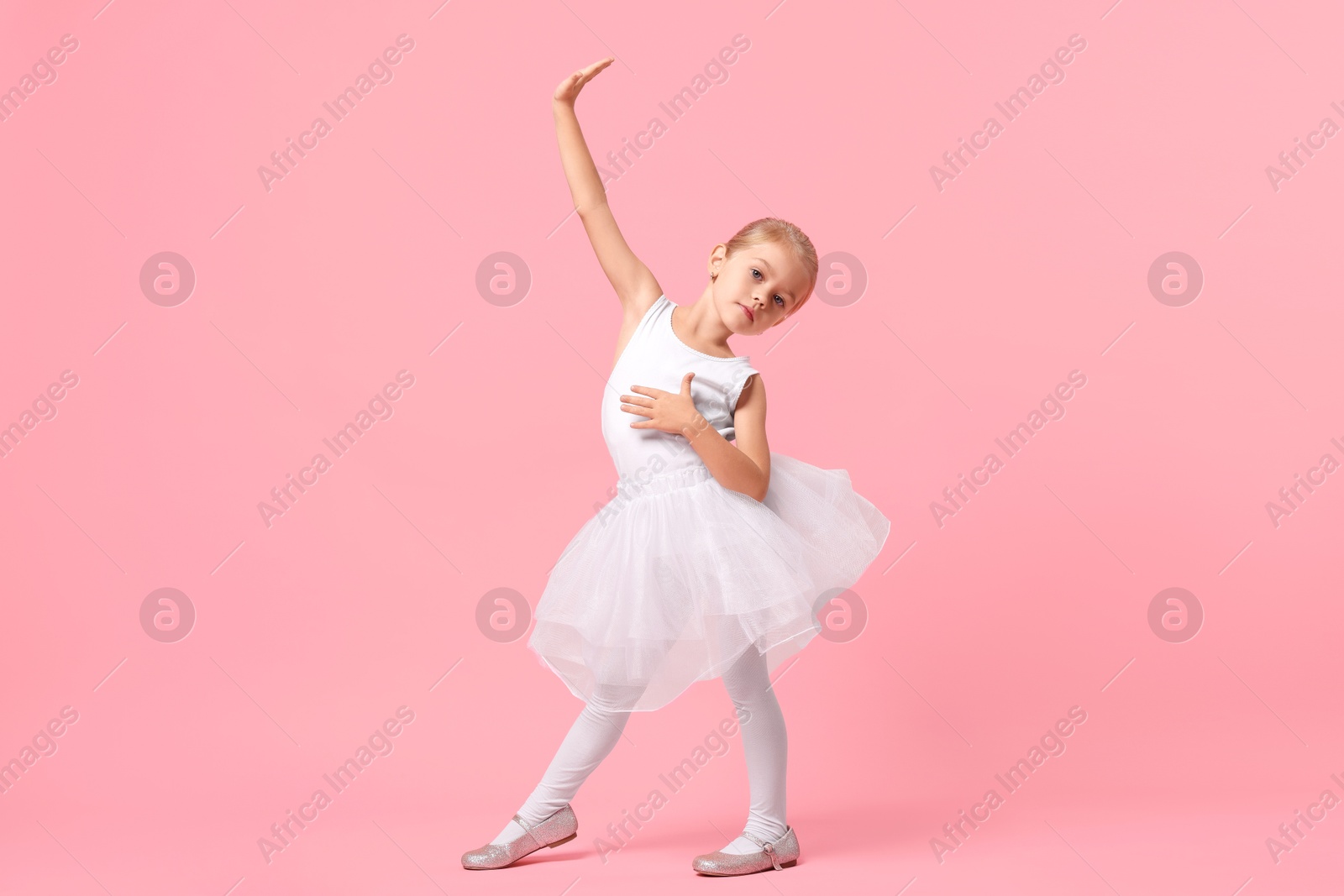 Photo of Little girl pretending to be ballerina on pink background. Dreaming of future profession