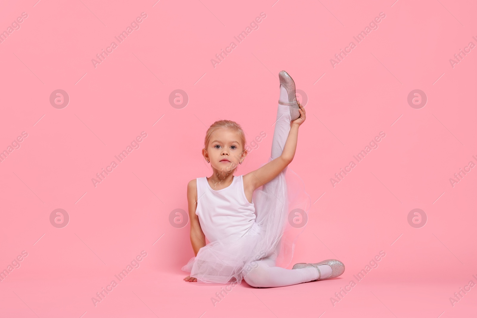 Photo of Little girl pretending to be ballerina on pink background. Dreaming of future profession