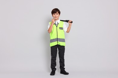 Photo of Boy pretending to be policeman on light grey background. Dreaming of future profession