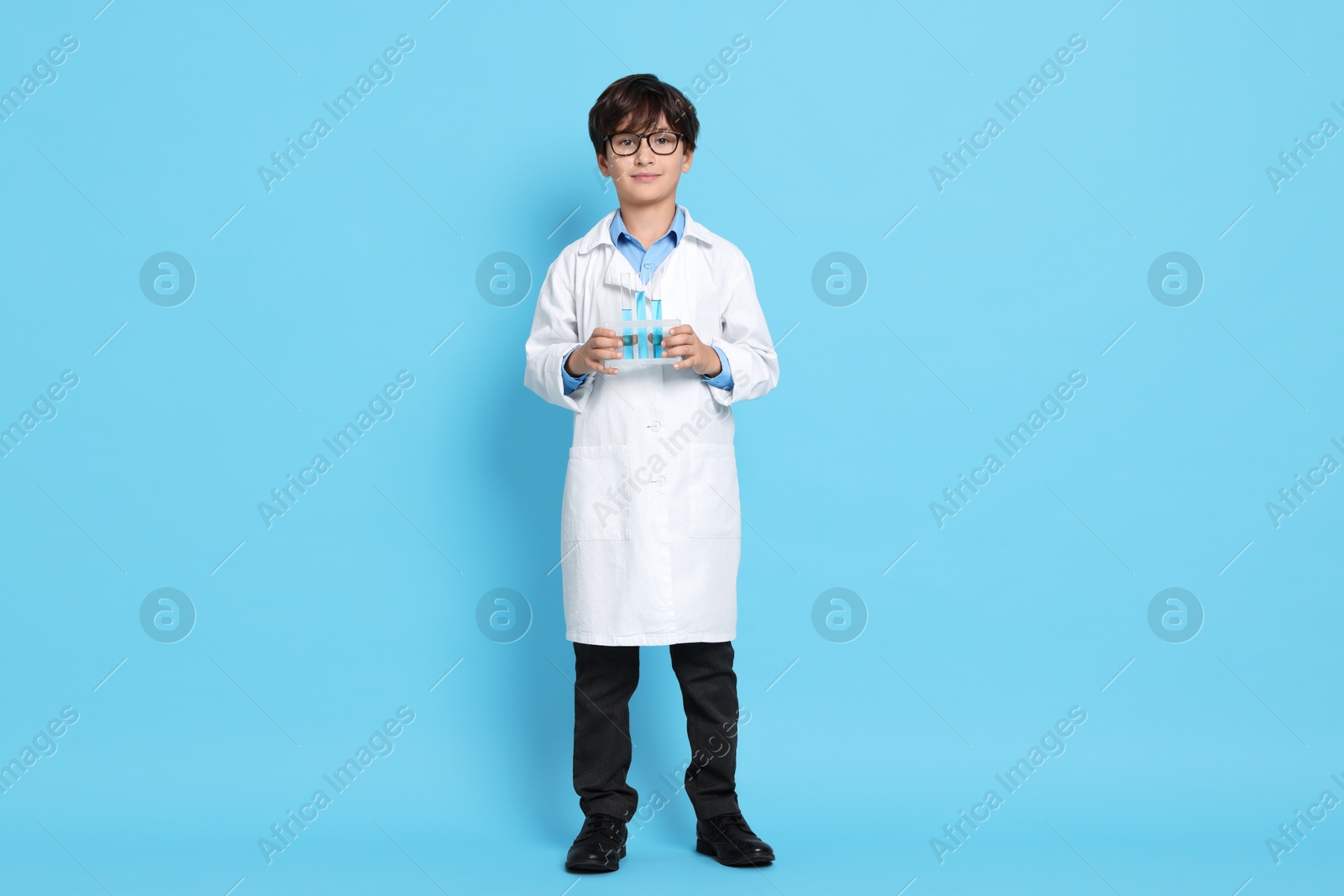 Photo of Boy with test tubes pretending to be scientist on light blue background. Dreaming of future profession