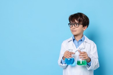 Photo of Boy with glassware pretending to be scientist on light blue background, space for text. Dreaming of future profession