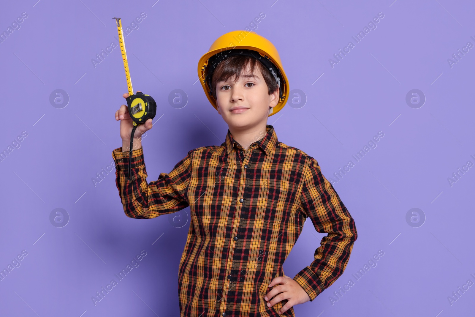 Photo of Boy with measuring tape pretending to be builder on violet background. Dreaming of future profession