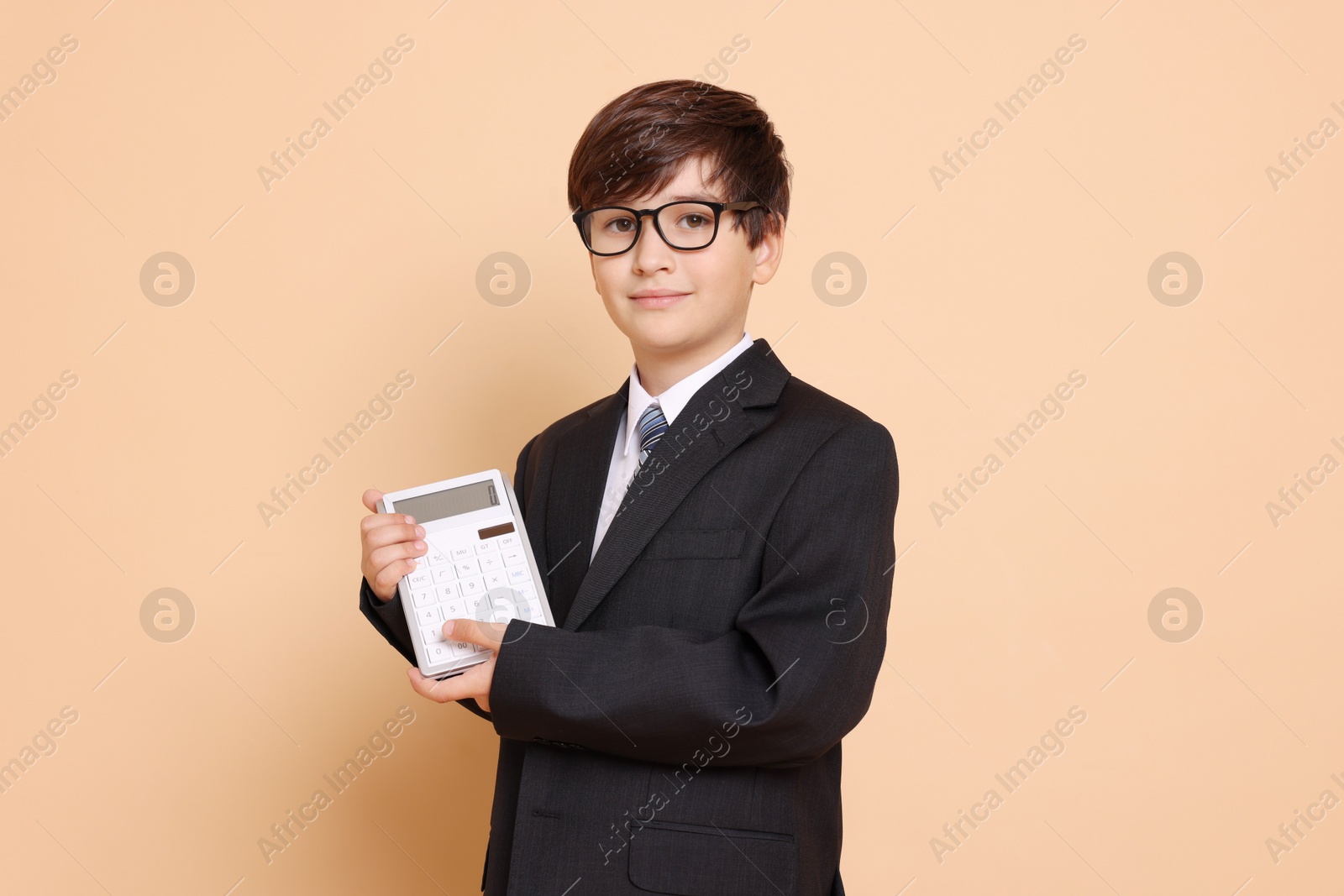 Photo of Boy with calculator pretending to be accountant on beige background. Dreaming of future profession