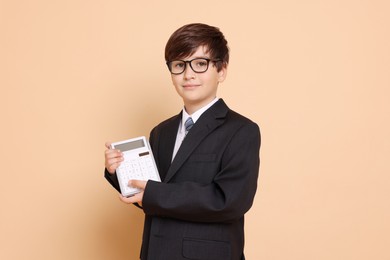 Photo of Boy with calculator pretending to be accountant on beige background. Dreaming of future profession