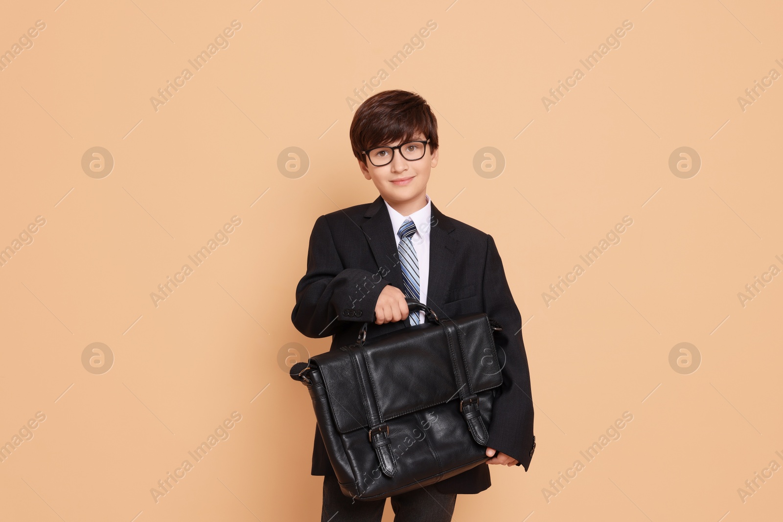 Photo of Boy in suit pretending to be businessman on beige background. Dreaming of future profession