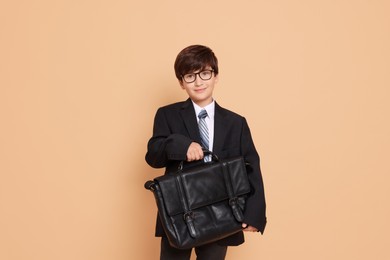 Photo of Boy in suit pretending to be businessman on beige background. Dreaming of future profession