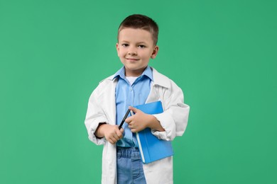 Photo of Little boy with book pretending to be doctor on green background. Dreaming of future profession