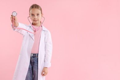 Photo of Girl with stethoscope pretending to be doctor on pink background, space for text. Dreaming of future profession