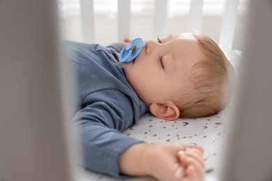 Photo of Cute baby sleeping in crib at home, closeup