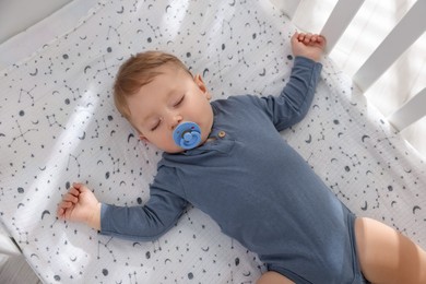 Photo of Cute baby sleeping in crib at home, top view