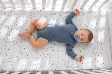 Photo of Cute baby sleeping in crib at home, top view