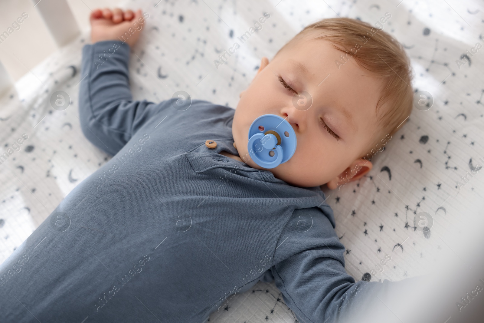 Photo of Cute baby with pacifier sleeping in crib at home