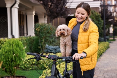 Photo of Woman with bicycle and cute Toy Poodle dog outdoors