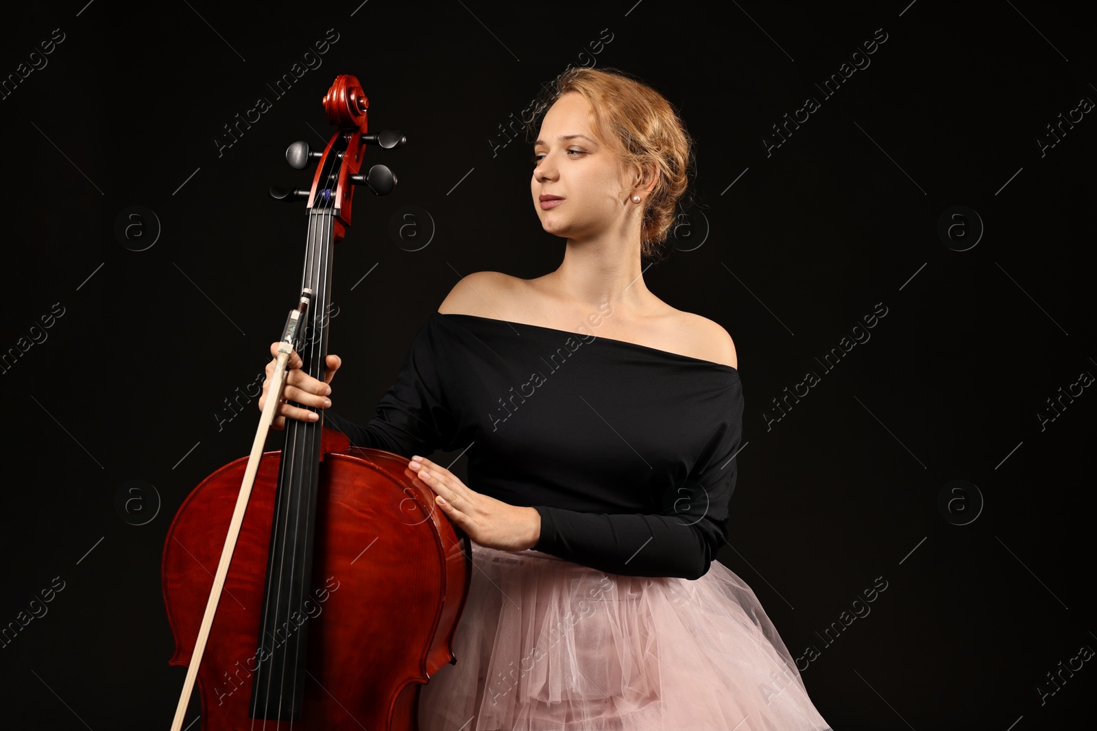 Photo of Beautiful young woman with cello on black background