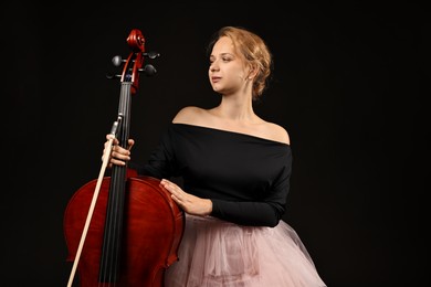 Photo of Beautiful young woman with cello on black background