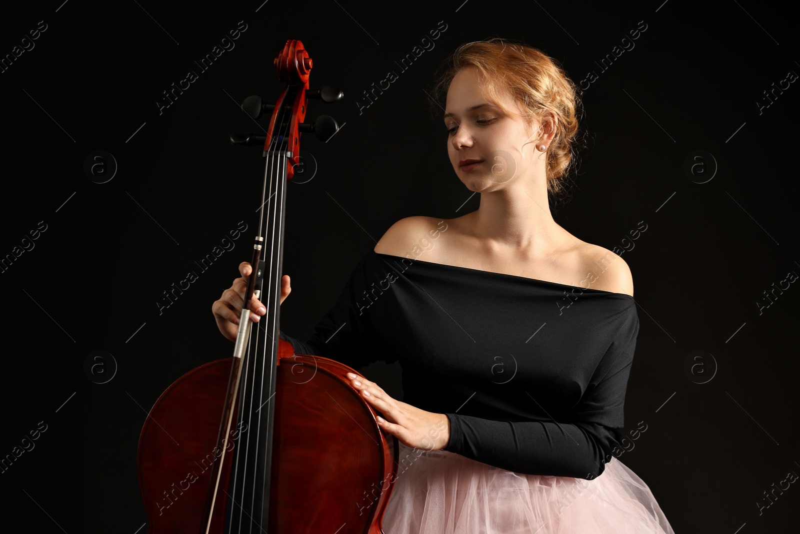 Photo of Beautiful young woman with cello on black background