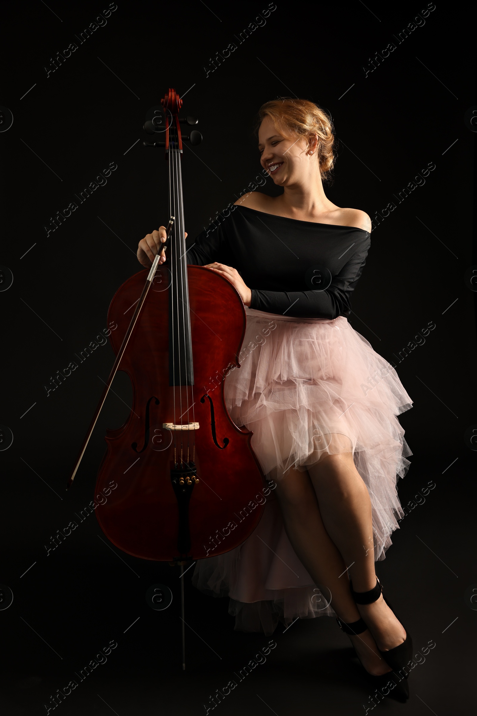 Photo of Beautiful young woman with cello on black background