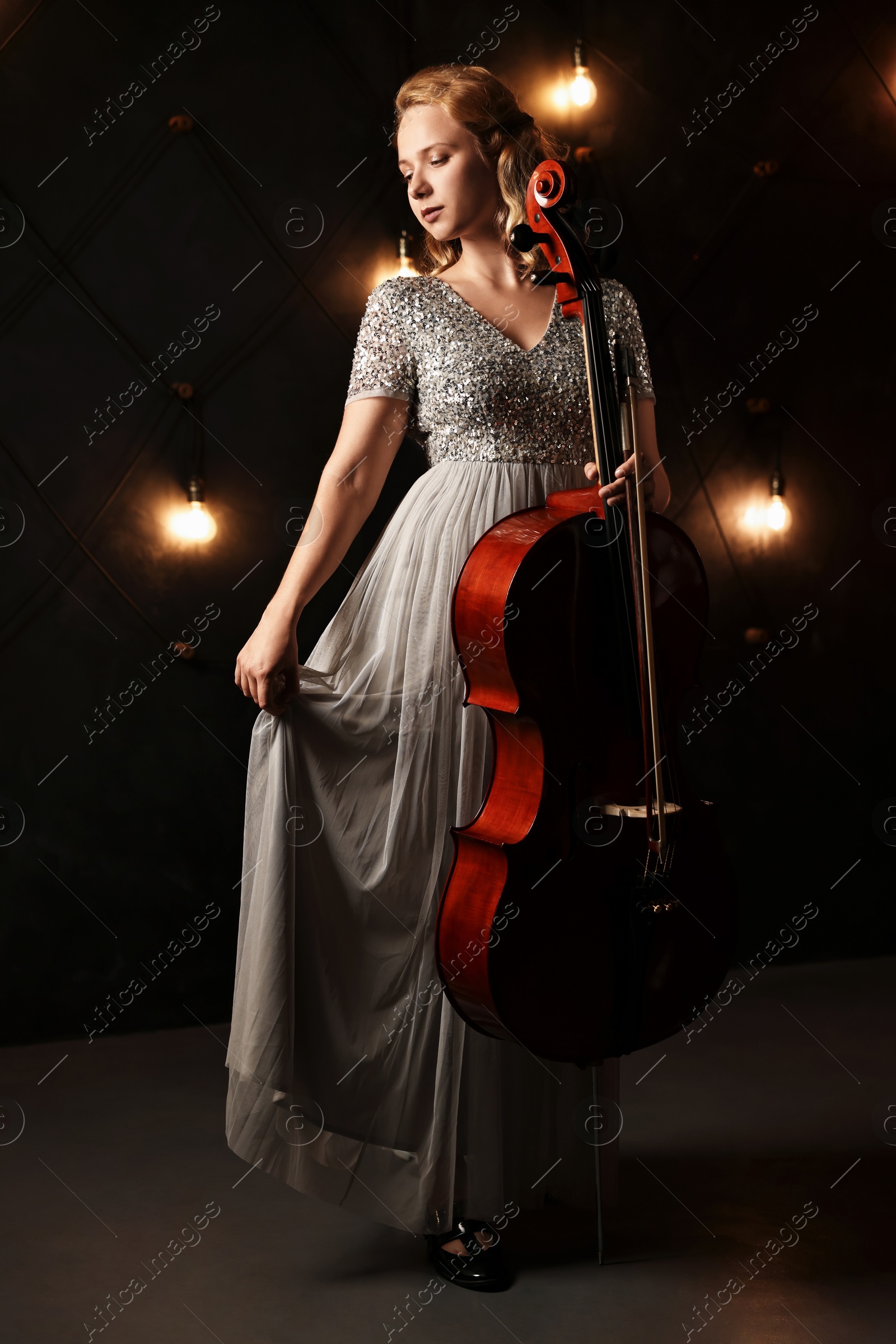 Photo of Beautiful young woman with cello on stage. Classic musical instrument