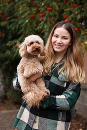 Woman with cute Toy Poodle dog in park