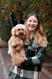 Woman with cute Toy Poodle dog in park