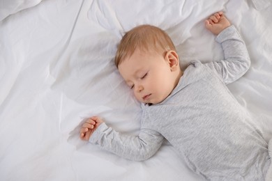 Photo of Cute little baby sleeping on bed at home, top view