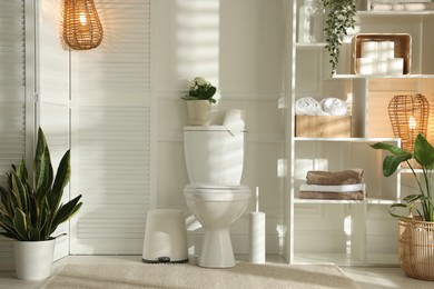 Photo of Folding screen, toilet bowl and houseplants in restroom