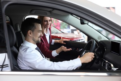 Photo of Happy saleswoman and client inside new car in salon