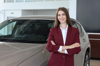 Photo of Happy saleswoman near new silver car in salon