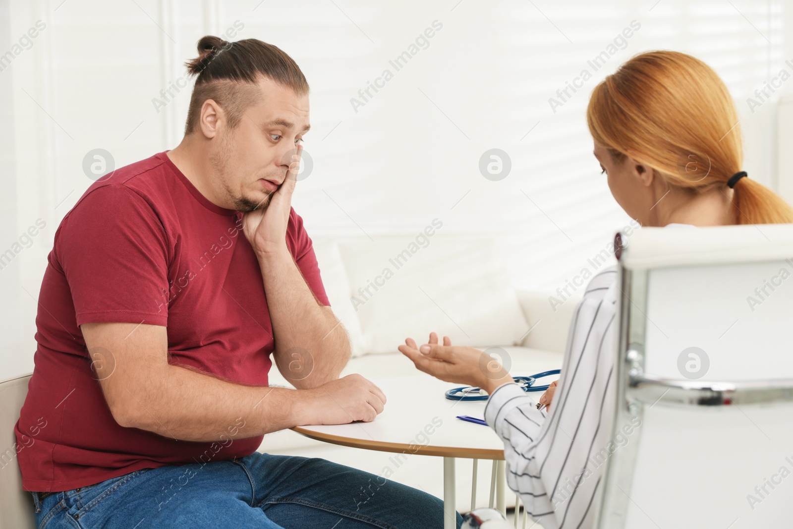 Photo of Overweight man having consultation with nutritionist at table in clinic