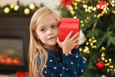 Photo of Little girl with Christmas gift at home