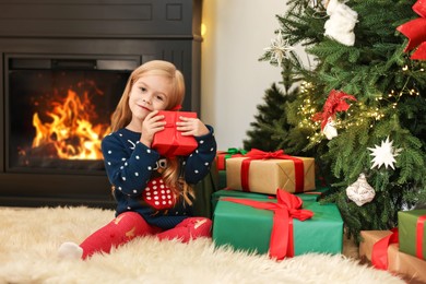 Photo of Little girl with Christmas gifts on floor at home