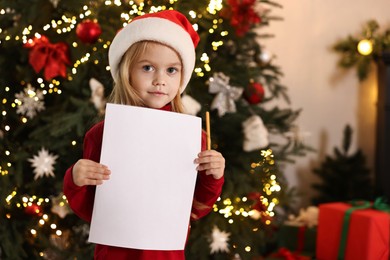 Little girl with letter for Santa Claus at home. Christmas celebration