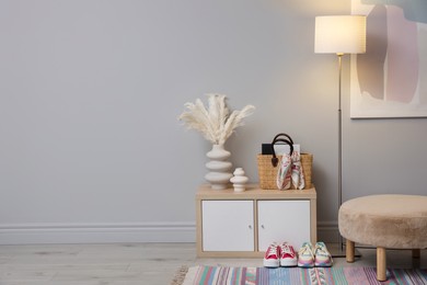 Photo of Stylish hallway interior with pouf and lamp. space for text