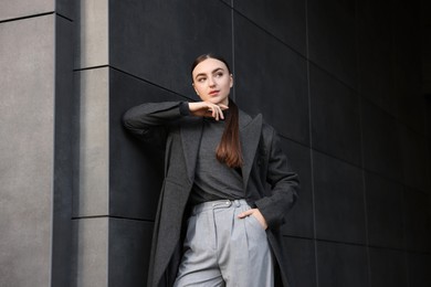 Photo of Beautiful young woman with black coat posing outdoors