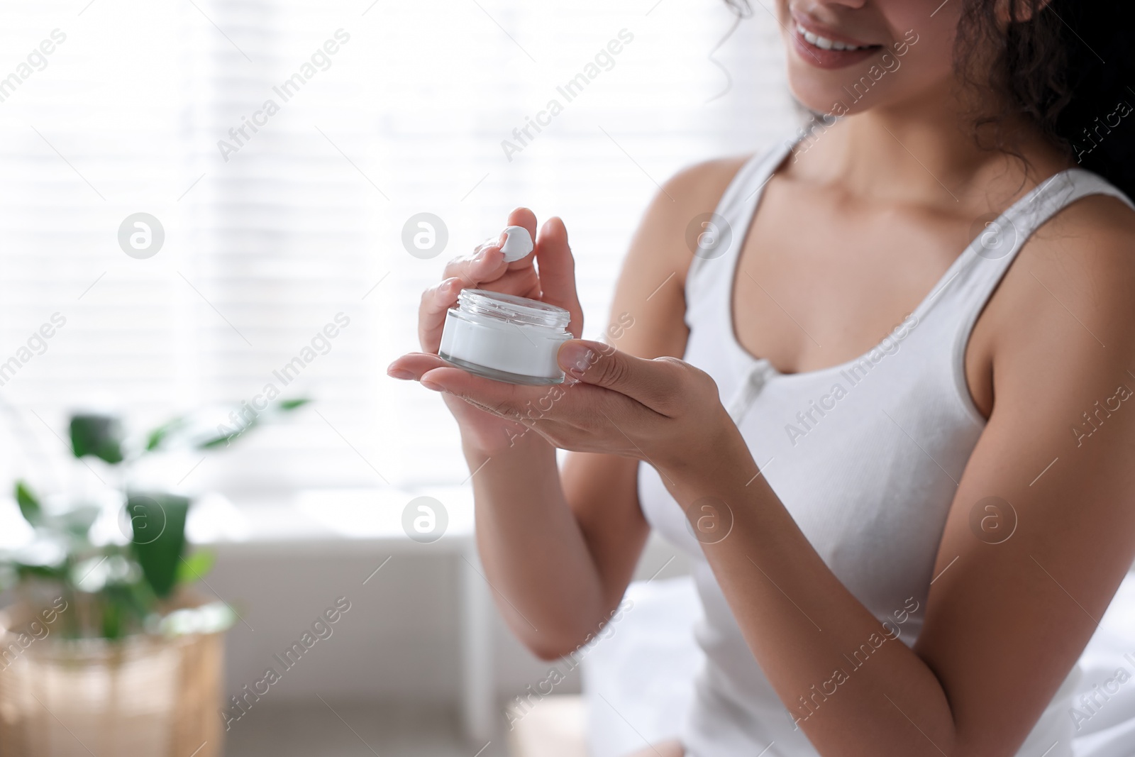 Photo of Woman with jar of cream at home, closeup. Space for text