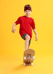 Photo of Little boy with skateboard on yellow background