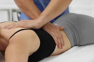 Photo of Osteopath massaging woman's back in clinic, closeup. Manual therapy