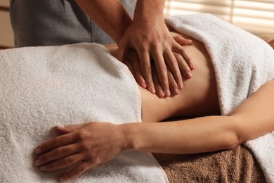 Osteopath massaging woman's belly indoors, closeup. Manual therapy