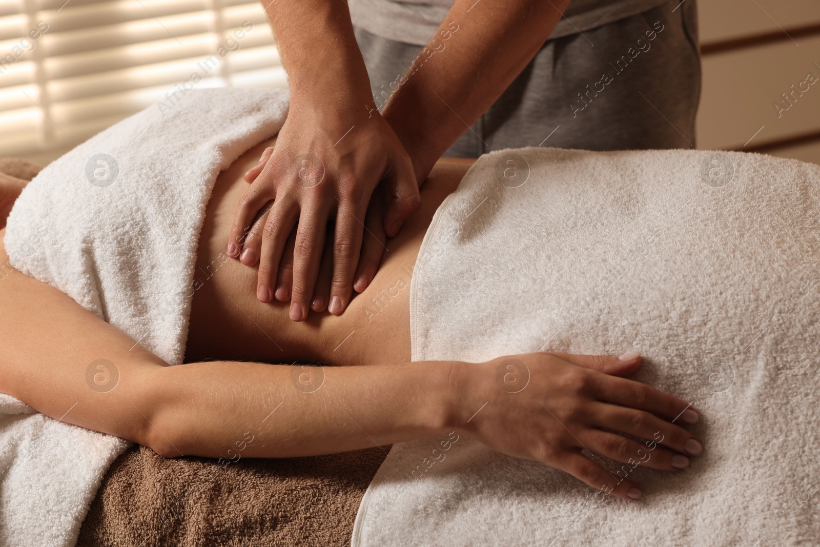 Photo of Osteopath massaging woman's belly indoors, closeup. Manual therapy