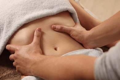 Photo of Osteopath massaging woman's belly indoors, closeup. Manual therapy