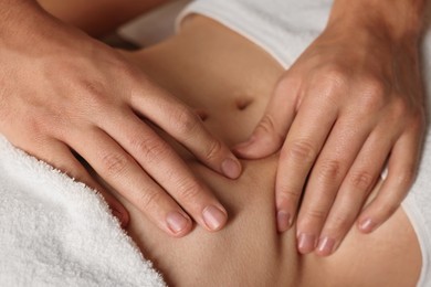 Photo of Osteopath massaging woman's belly indoors, closeup. Manual therapy