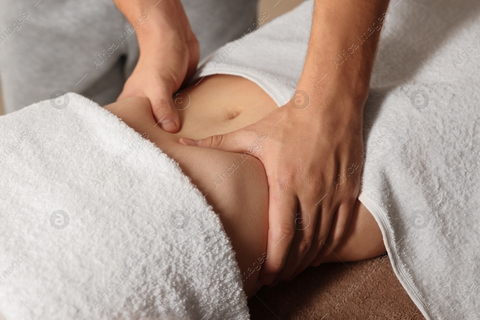 Photo of Osteopath massaging woman's belly indoors, closeup. Manual therapy