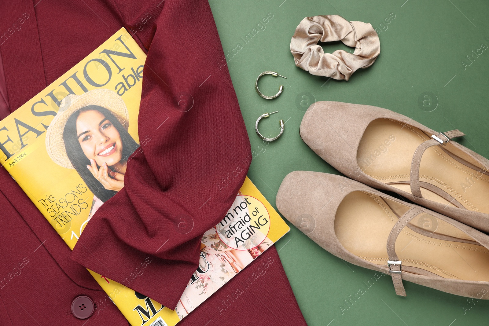 Photo of Pair of ballet flats, magazine, jacket and accessories on green background, flat lay