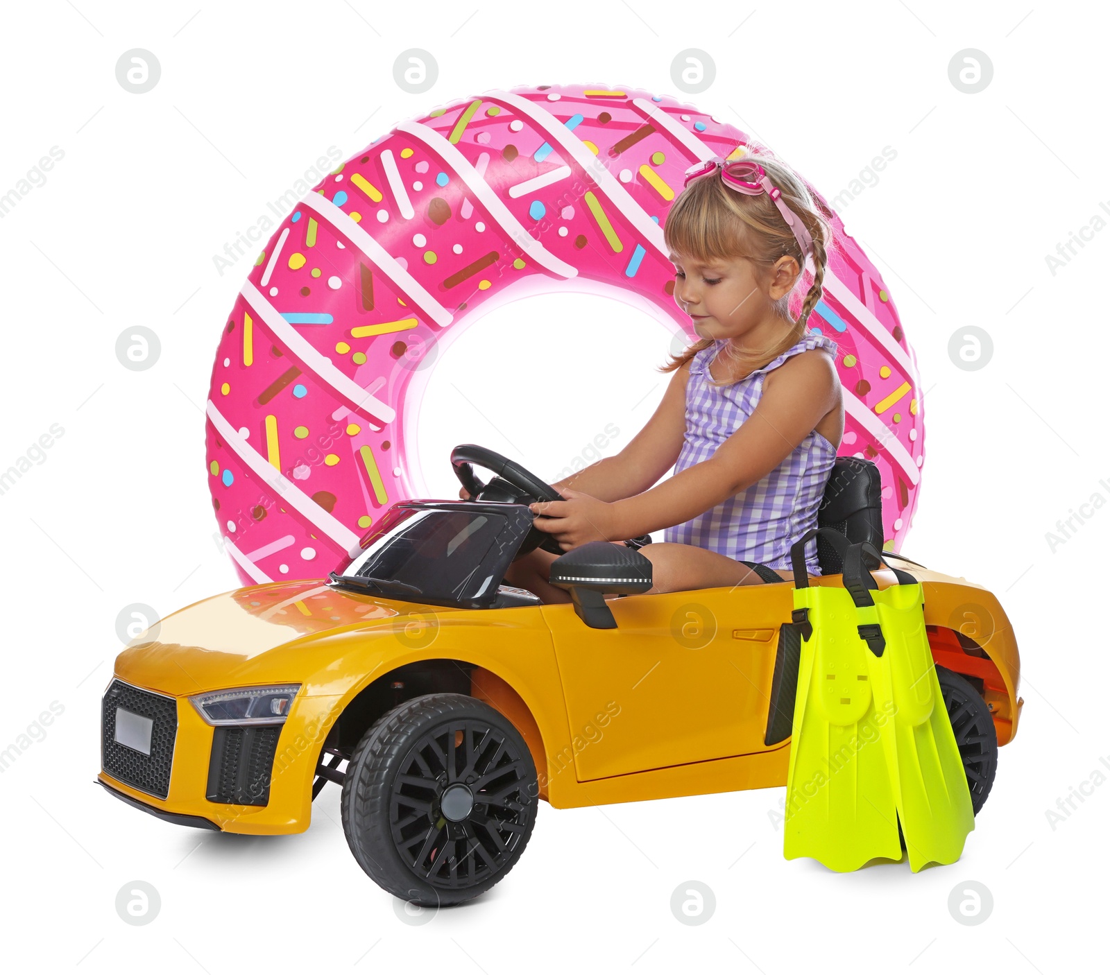 Photo of Cute little girl in swimsuit with inflatable ring, flippers and toy car on white background