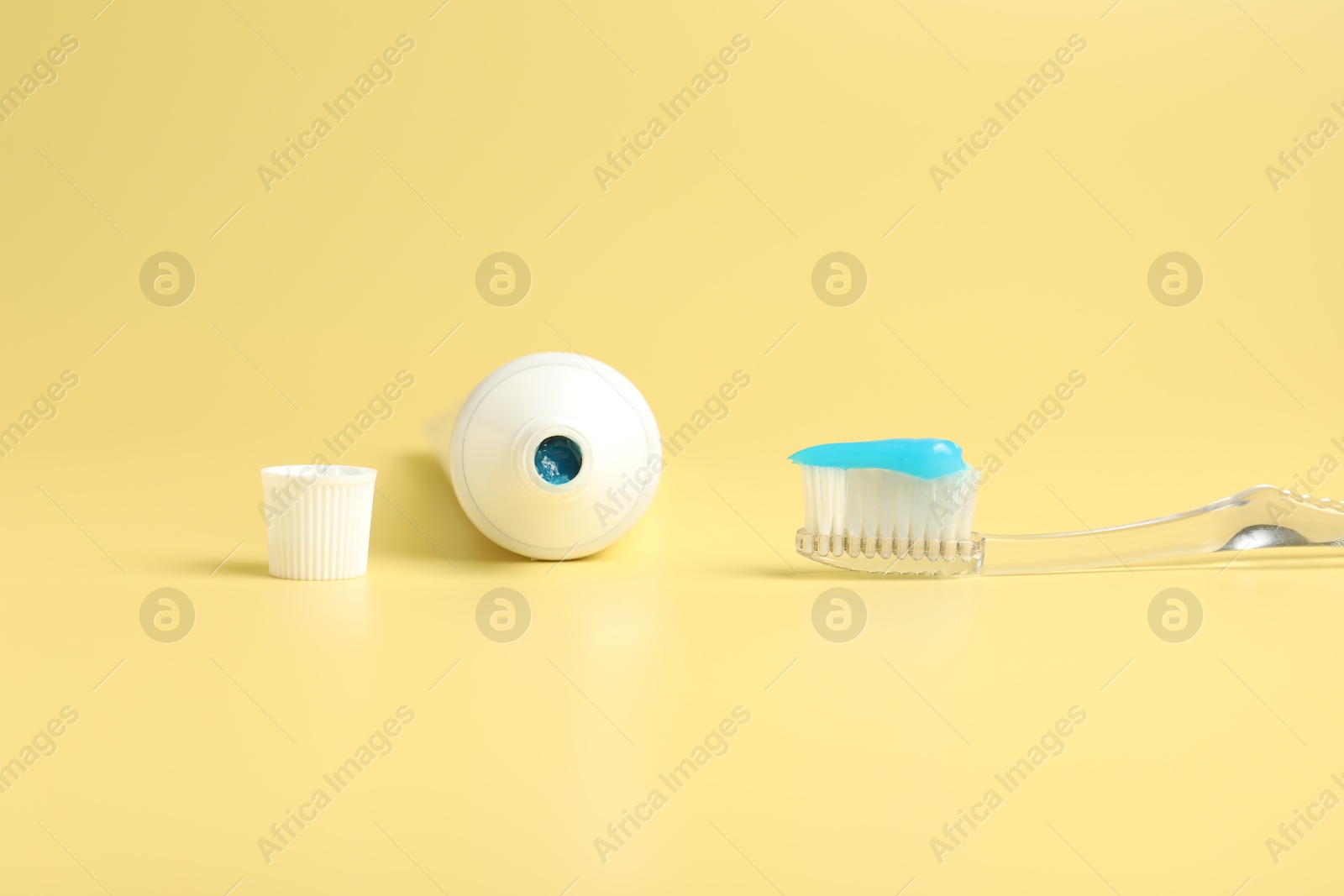 Photo of Toothbrush with toothpaste and tube on yellow background