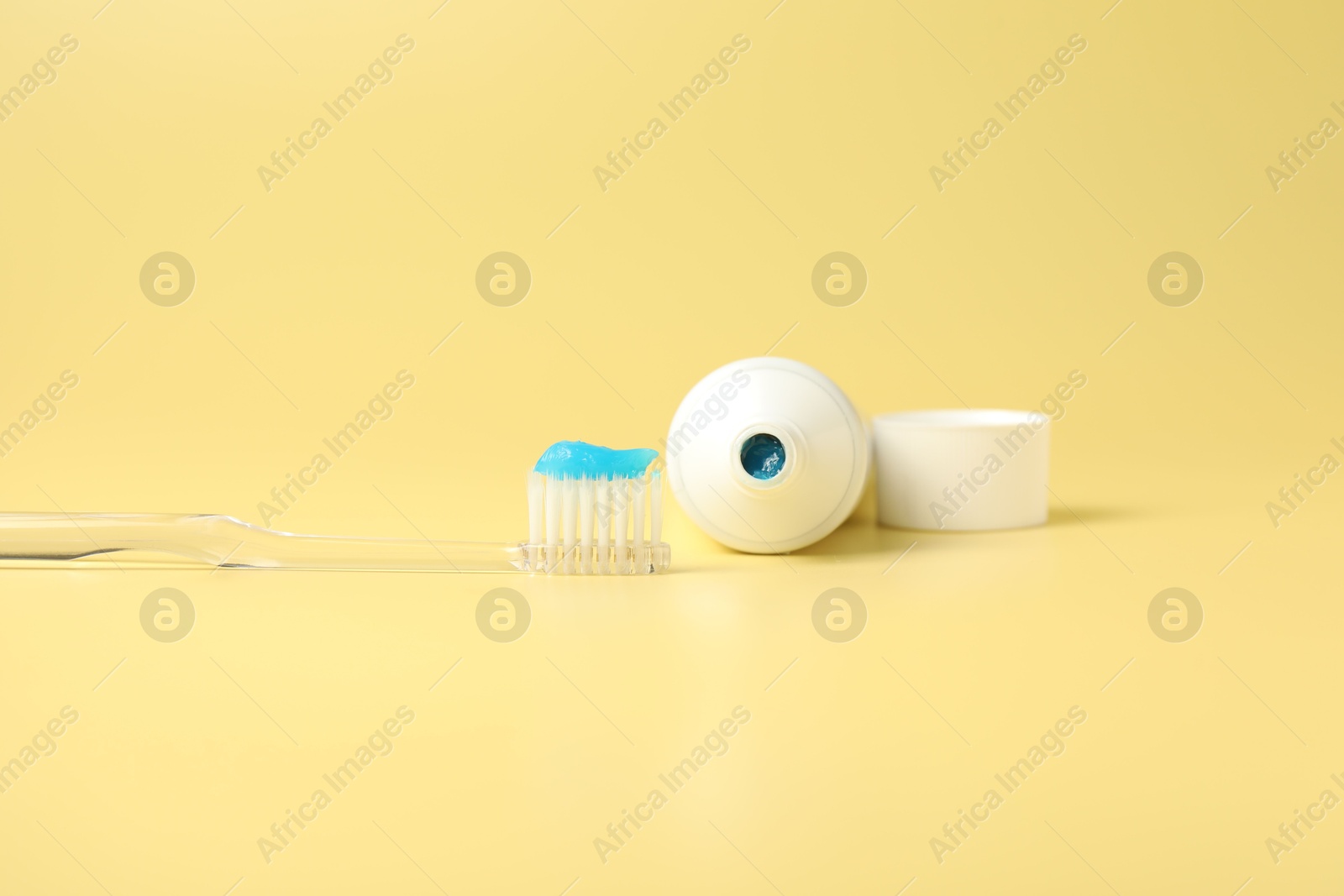 Photo of Toothbrush with toothpaste and tube on yellow background