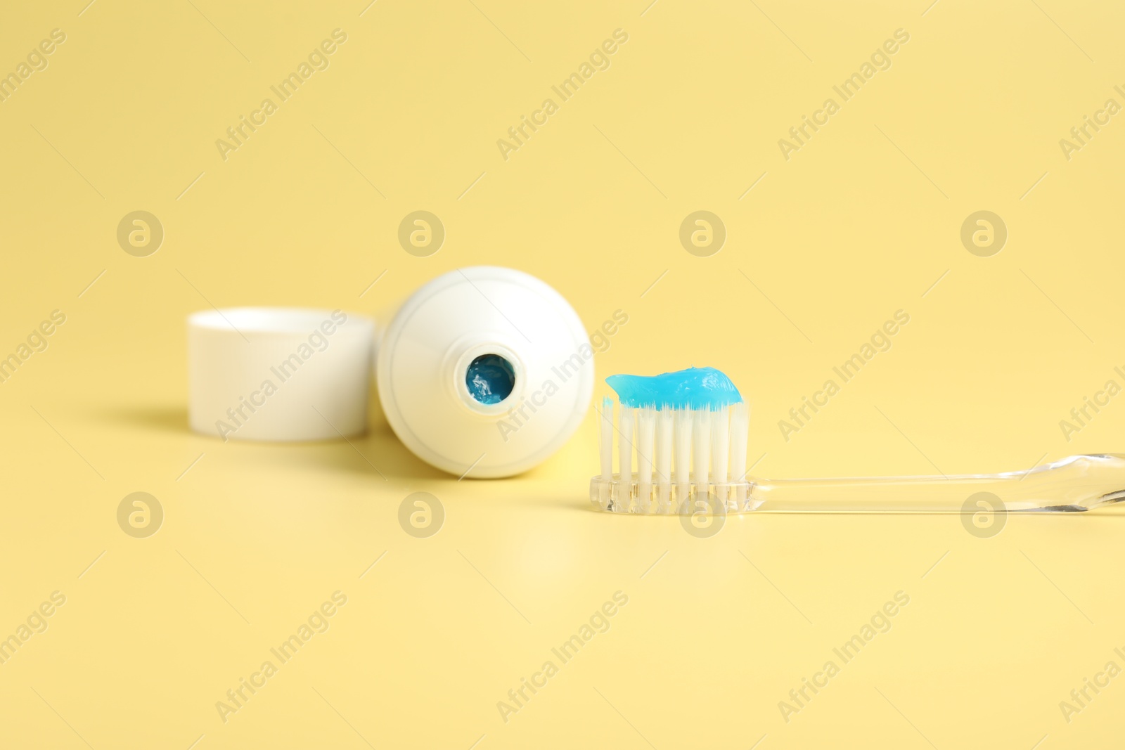 Photo of Toothbrush with toothpaste and tube on yellow background, closeup